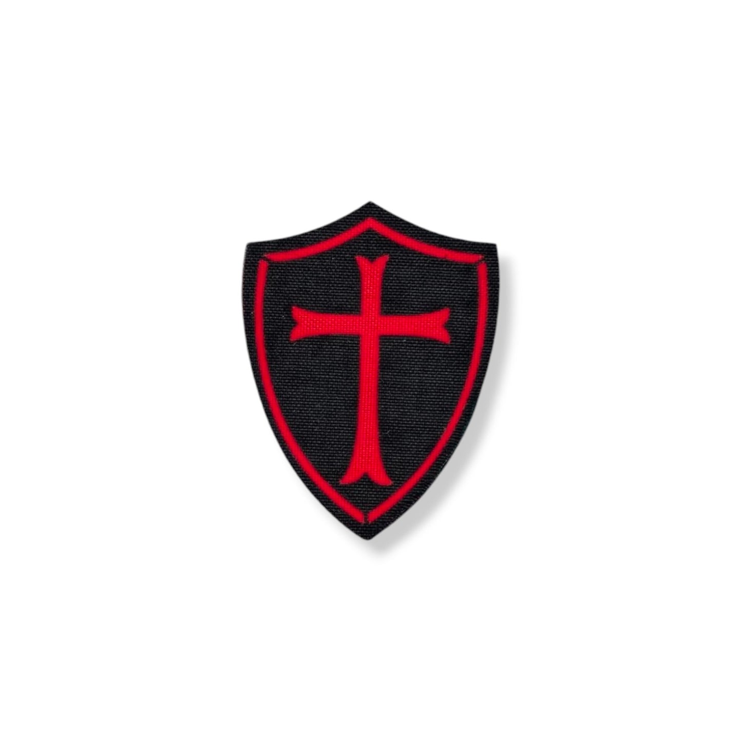 A shield-shaped patch with a crusader cross design, predominantly in a green camouflage pattern.